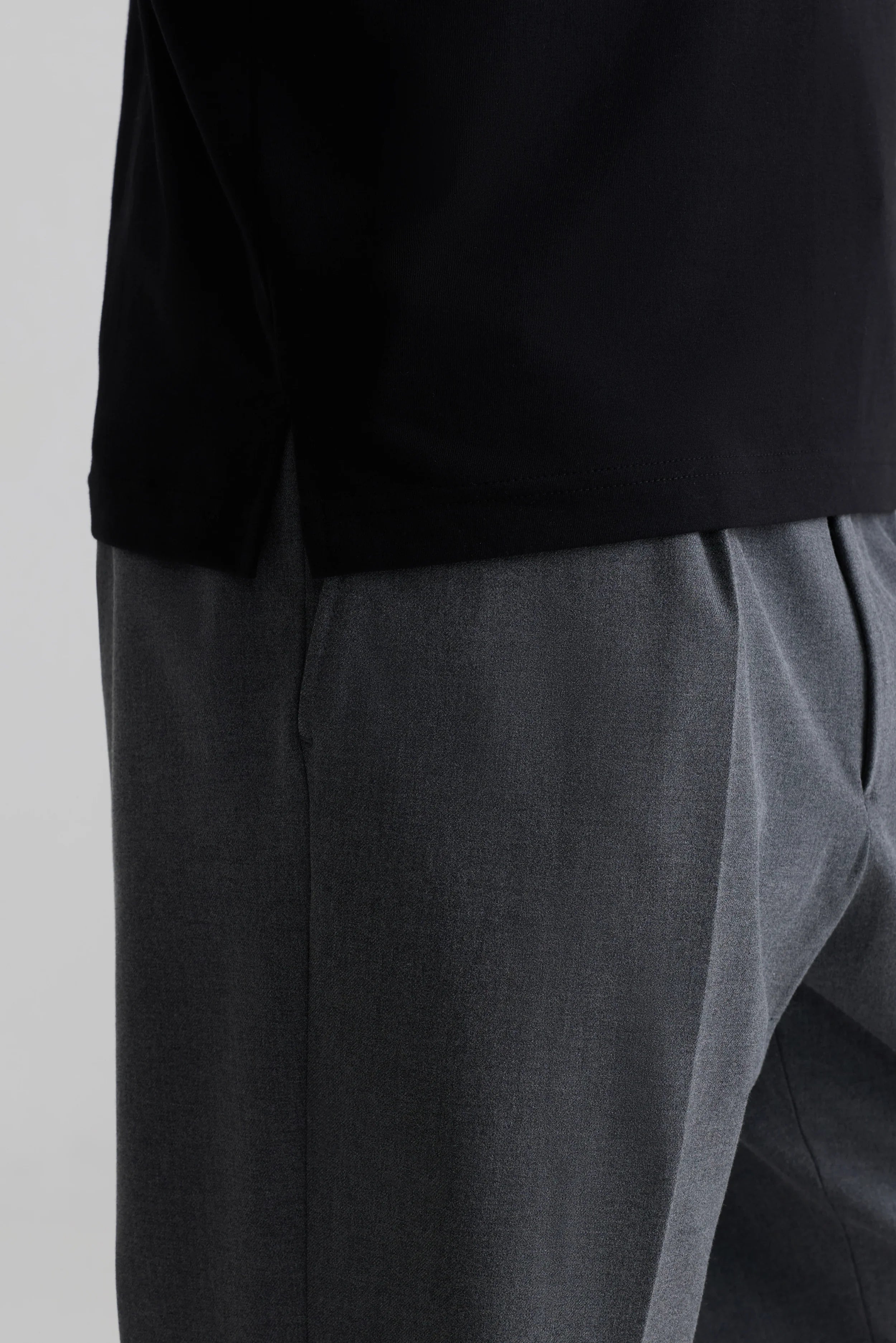 Black minimalist t-shirt with grey pleated trousers, designed for everyday comfort and style.