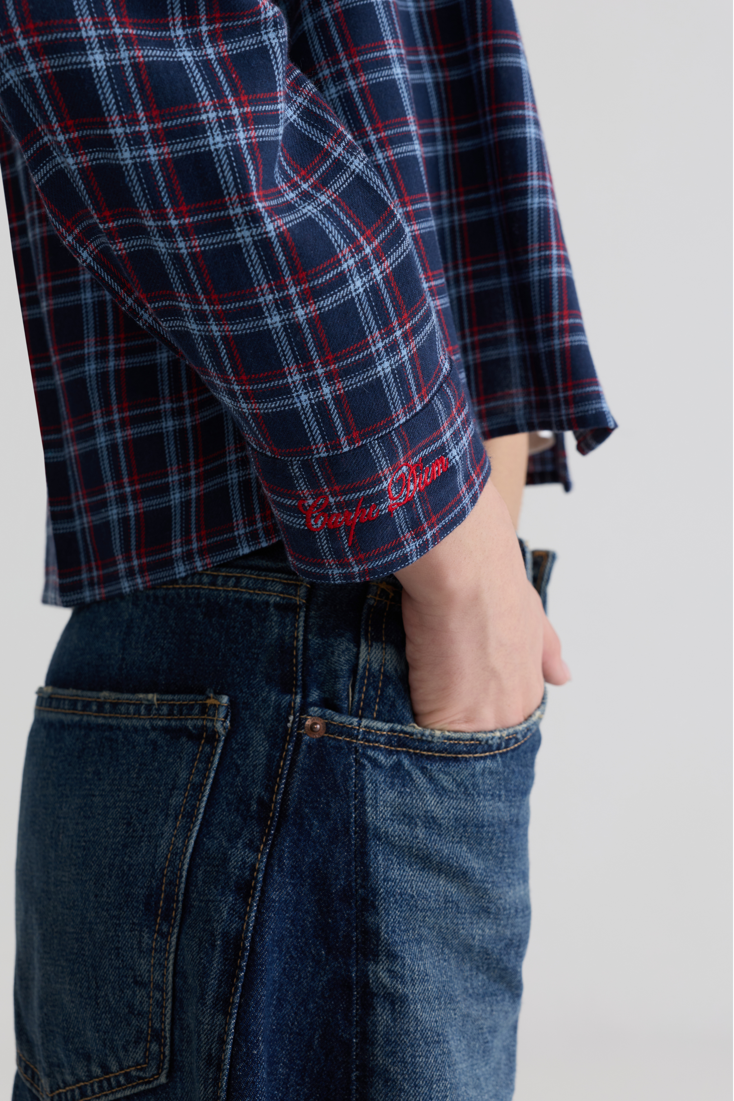 “Blue check flannel shirt cuff with red handwritten Carpe Diem secondary logo detail