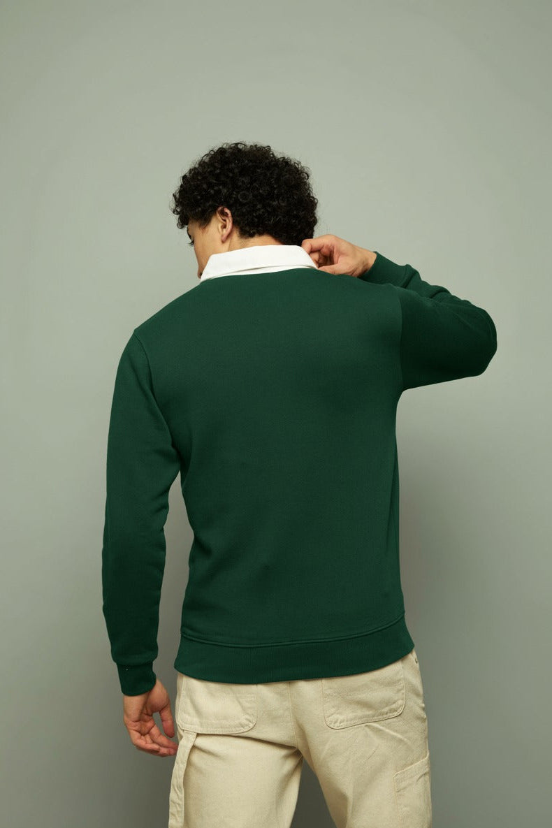 Person wearing a forest green rugby polo sweatshort with a white collar against a gray background